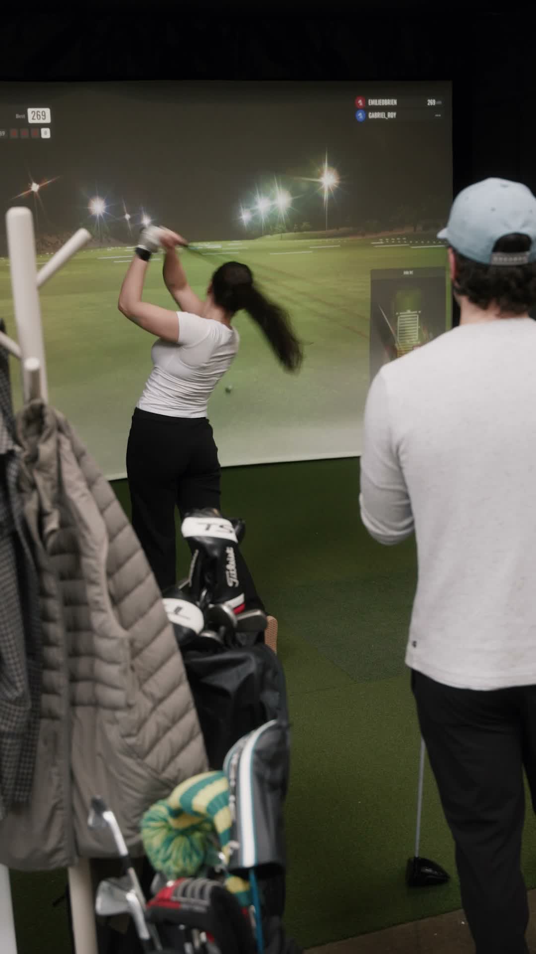 Joueuse et joueur partageant une station de golf intérieur